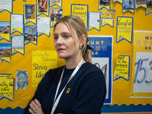 IRC ambassador, Romola Garai, stands with her arms folded in an IRC classroom.
