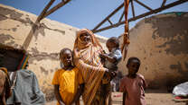 Altuma stands in her temporary house with her three children.