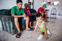 Cibel's youngest son, Matías, plays at home with his cousin, aunt and older brother nearby.