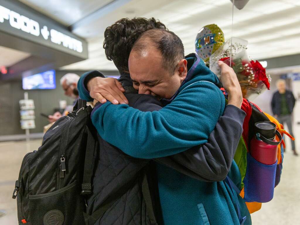 Two family members embrace after finally being reunited at an airport in the U.S.