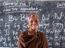 A girl stands in front of a school chalkboard.