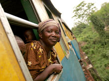 Congolese woman sticking head out of moving railroad car en route to market.