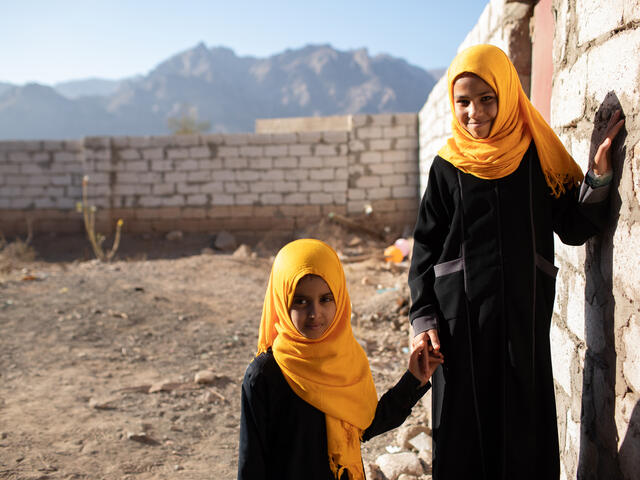 Två unga flickor håller varandra i händerna i Jemen. 