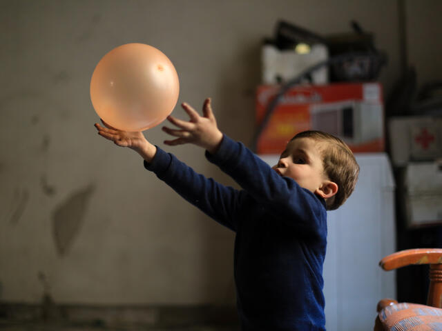 Syrian boy in underground bunker plays with a balloon