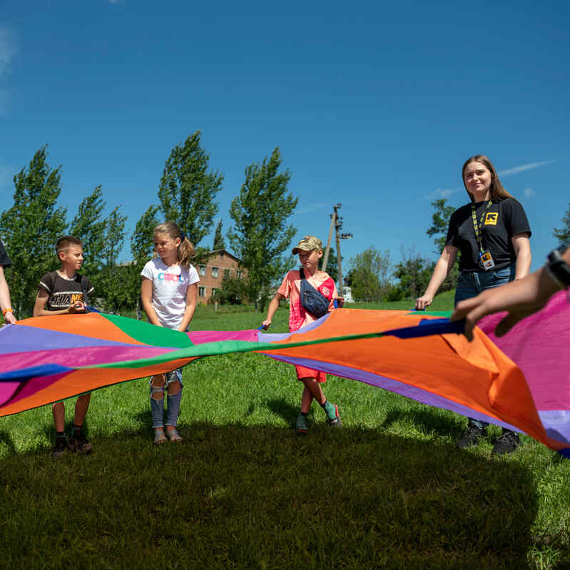 A group of people people playing with a ribbon kite.
