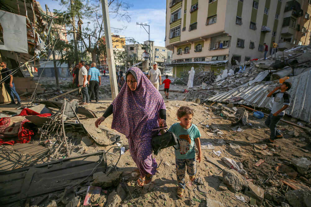 한 엄마와 아이가 이스라엘의 공습으로 파괴된 가자 지구를 걸어가고 있습니다.