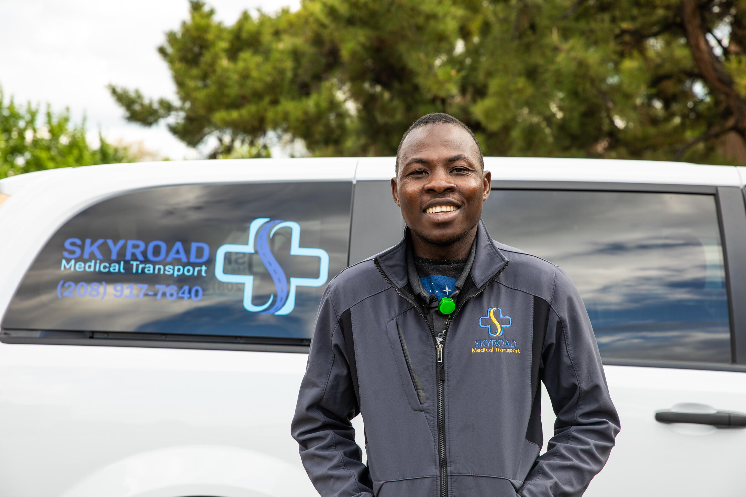 Jonathan Amissa stands in front of a van this is part of his company's fleet of medical transport vehicles.