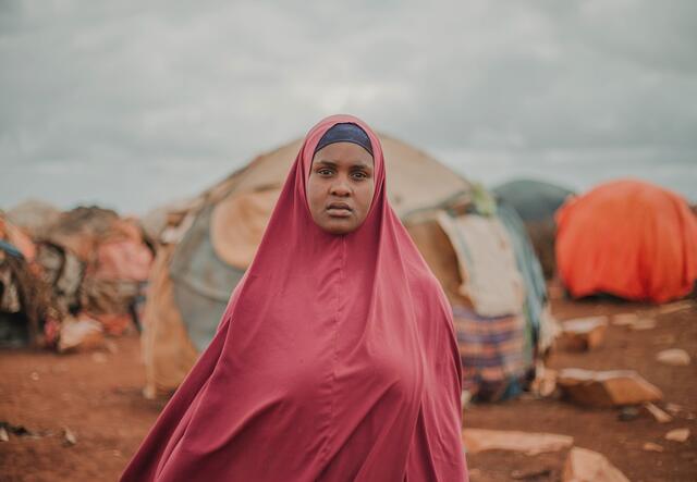 Woman stands in front of tents in Somali displacement camp