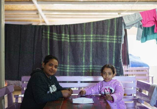 Maria and daughter Ashley sit at a table, facing the camera.