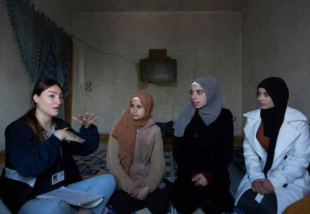 Sabah and other refugee girls sitting with IRC Women's Protection and Empowerment Assistant Elissar Hababe