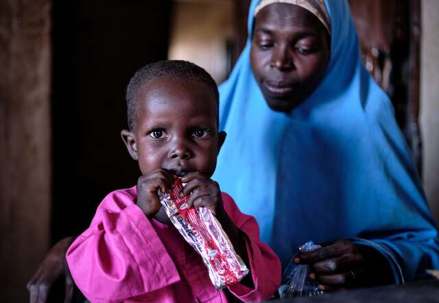 A young boy eats a malnutrition treatment packet, provided by the IRC in Nigeria.