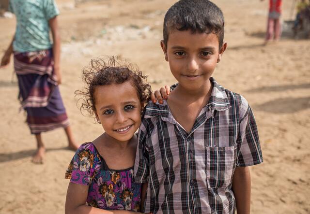 A girl and boy stand in front of their home in Al Buraiqeh, a remote village on the outskirts of Aden, Yemen, where IRC health teams provide care for malnutrition,