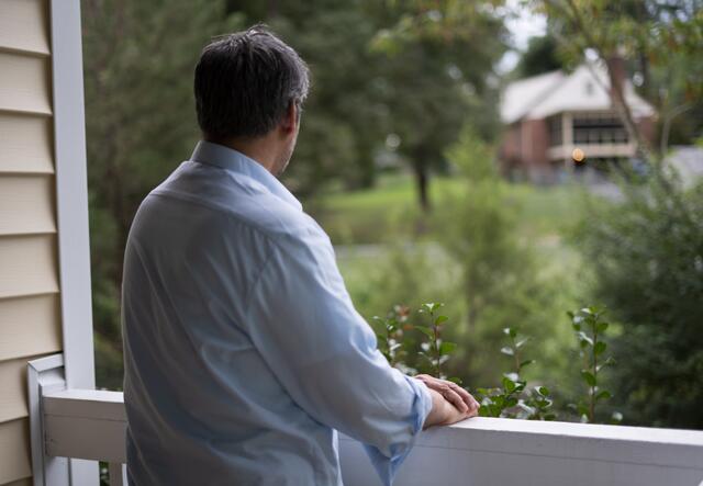 Afghan refugee Abdul, 52, stands alone on the porch of a friend's home in Virginia, looking out over the railing.