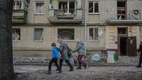 Three people walking past a building