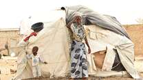 A mother and her son stand outside their temporary shelter in Burkina Faso.
