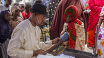 An IRC health worker checks an elderly woman's blood pressure