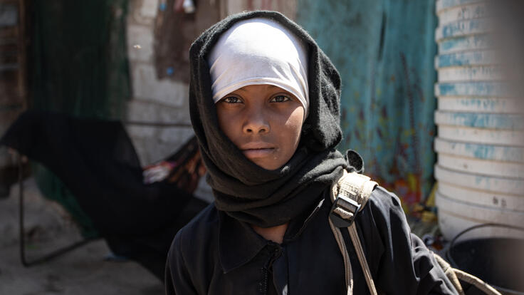 Ten-year-old Aisha, carrying her school bag in a camp for displaced families like hers in Yemen.