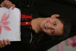 A portrait of Ruba who is holding her drawing.