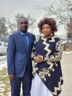 Omari, left, and Zaina stand side by side in formal attire outside their home.