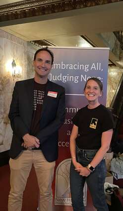 Film director standing with IRC staff member in front of banner.