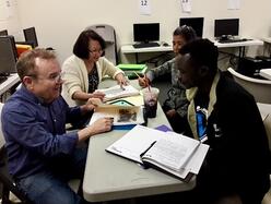 Civics and Citizenship Volunteer tutor, Tom, is tutoring students in person in a classroom 