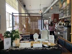 Table filled with jewelry in a coffee shop. People in line ordering food and coffee.