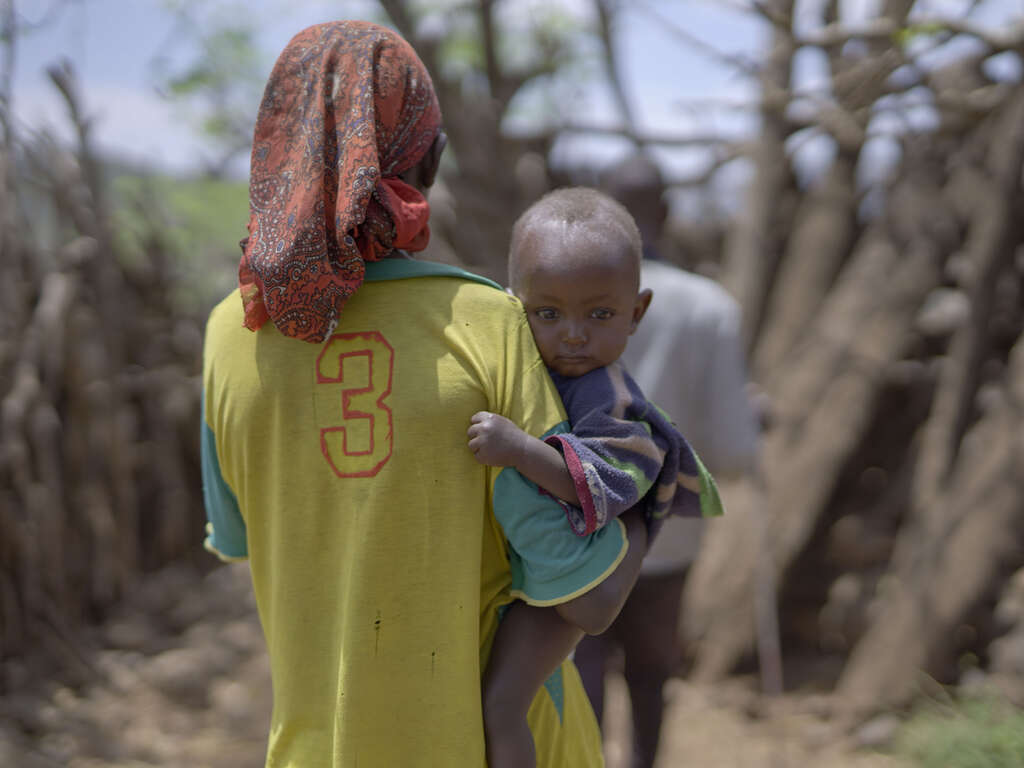 에티오피아 한 어린이가 엄마 품에 안겨 카메라를 바라보고 있습니다.