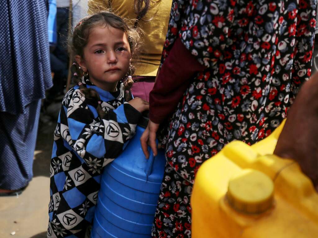 A young girl and a woman line up with empty water containers in the central Gaza strip. 