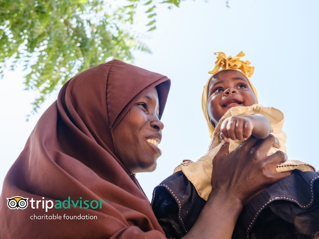 A woman wearing a hijab smiling at a baby in her arms