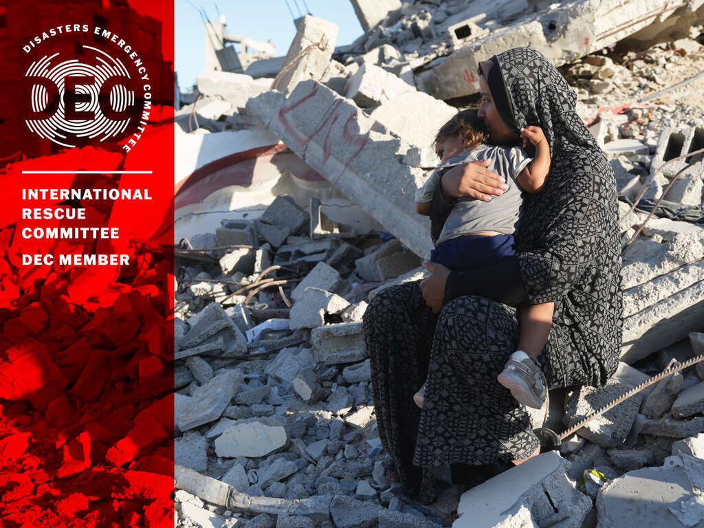 Woman holding a child amongst rubble in Gaza