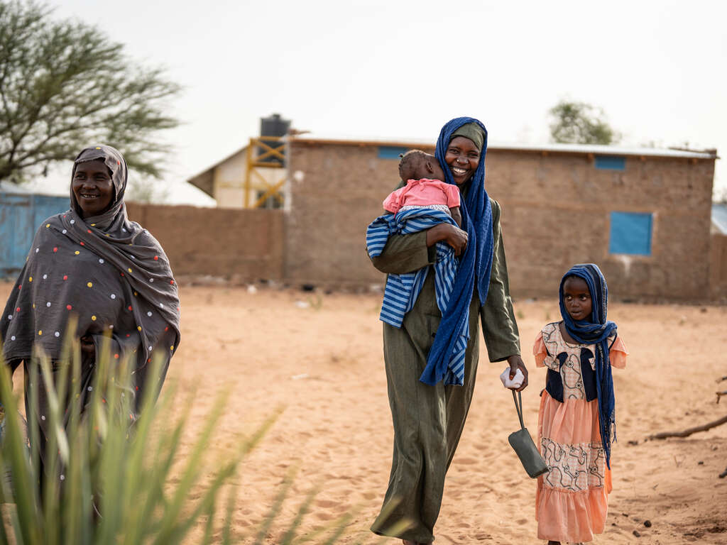 Kvinnor och barn som flytt kriget i Sudan går på en väg efter att ha besökt RESCUE:s hälsocenter i Tchad.