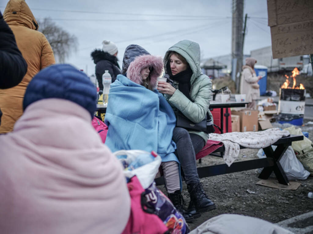 Ukrainska människor på flykt värmer sig