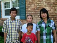 Father, mother, and two sons pose for picture in front of their new Abilene home which the IRC helped them move into.