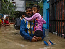 한 아버지가 홍수 속에서 딸을 품에 안고 탈출하고 있습니다.