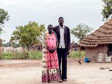 A man and woman embrace while posing for a photo outside their home in South Sudan.