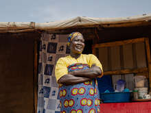 Eine Frau steht mit verschränkten Armen im Freien in Uganda.
