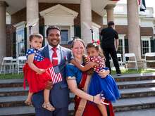 A family holding their two children and smiling into the camera