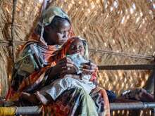 Frau hält ein kleines Kind auf ihrem Arm.