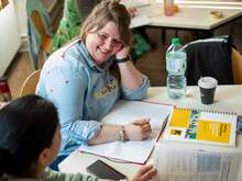 Zwei Personen arbeiten gemeinsam mit Büchern und Notizen an einem Projekt