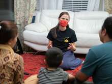 34-year-old Afghan translator Ali, is seen from behind seated on the floor with his wife and two young children as they speak with a female IRC staff member in Richmond, Virginia.