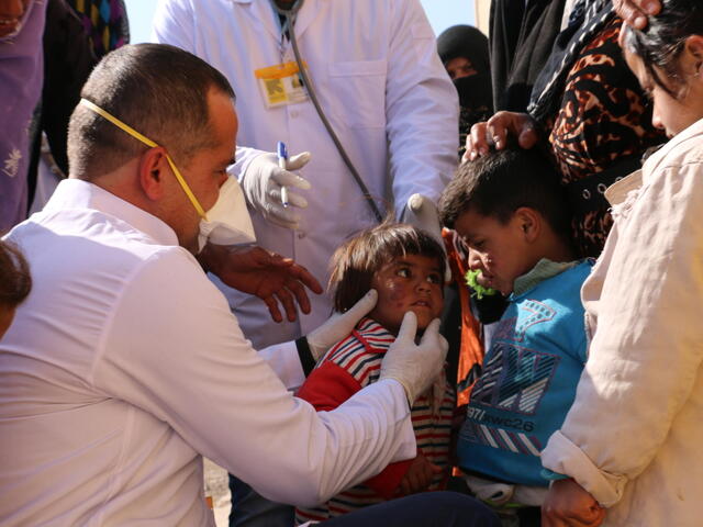 A employee of IRC examines a child