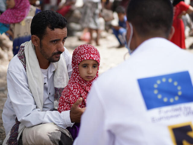 A father sits with his daughter talking to a doctor in a white coat