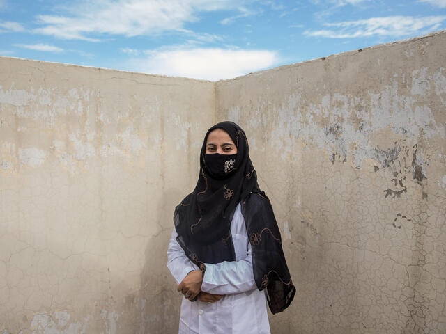 Amna Gul stands in front of a wall and looks at the camera 