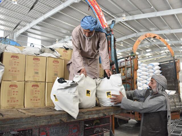 Men work to unload a truck full of food supplies in a warehouse