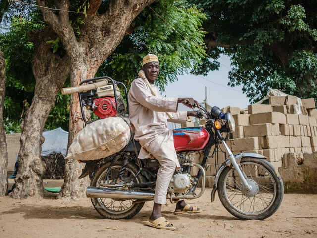 Man sitting on a motorcycle with a water-pump on the back