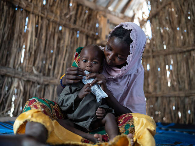 Frau gibt ihrem Kind Nährstoffe in Form von proteinreicher Erdnusspaste in Tschad.
