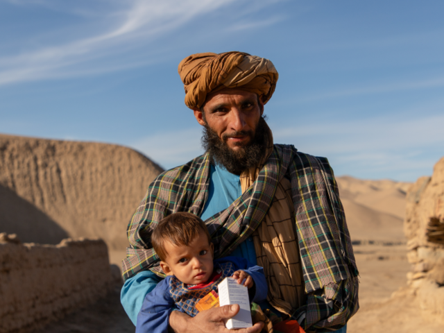 Man standing in arid landscape with child and food items