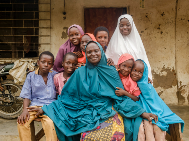 Woman with her family sitting outside her home on a bench smiling
