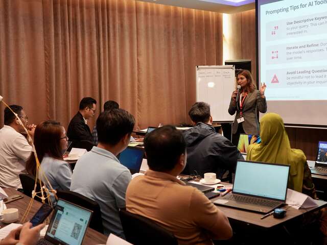 At the workshop, the trainer is emphasizing the importance of impactful prompts and discusses the significance of context, specificity, and relevance in prompt creation during interactive workshops using AI tools.