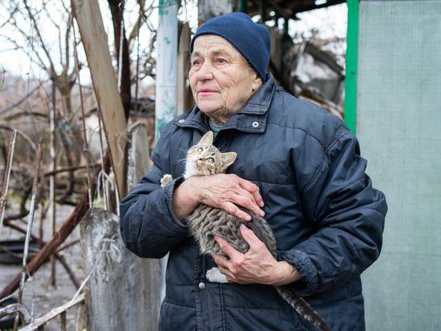 En äldre kvinna i ett kallt Ukraina under vintern håller sin katt i famnen 